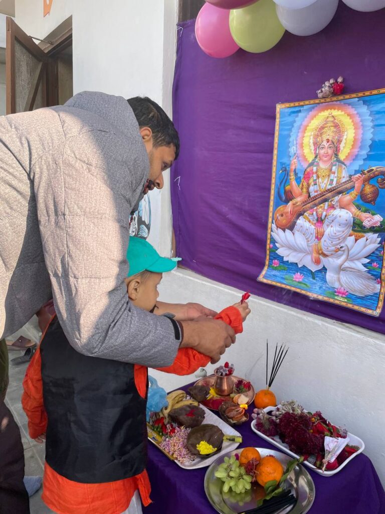 Los niños y profesores se congregan para decorar una mesa con la imagen de Saraswati, rodeada de flores, velas e incienso.